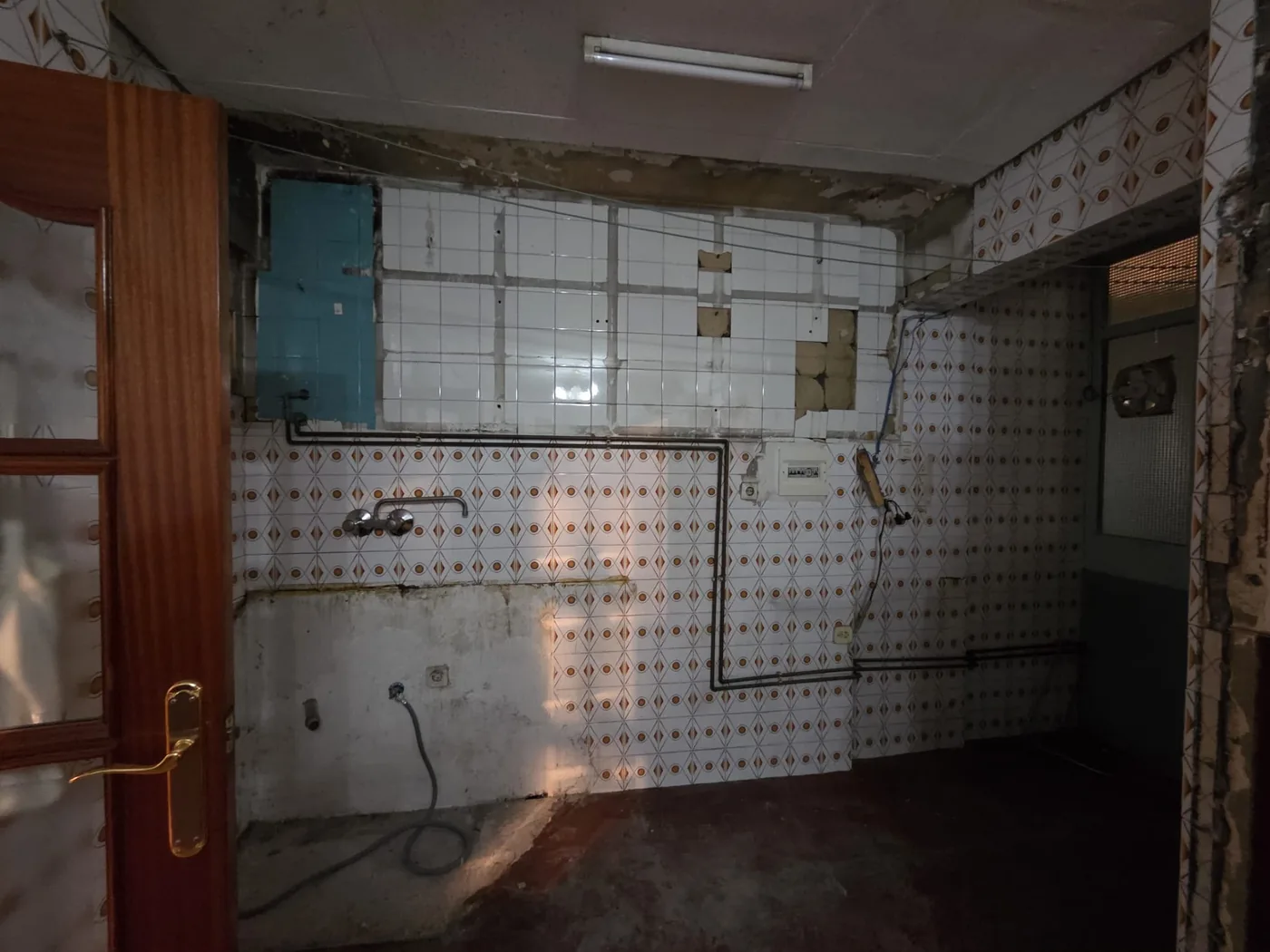 Cocina antes de la reforma, con azulejo antiguo e instalaciones a la vista