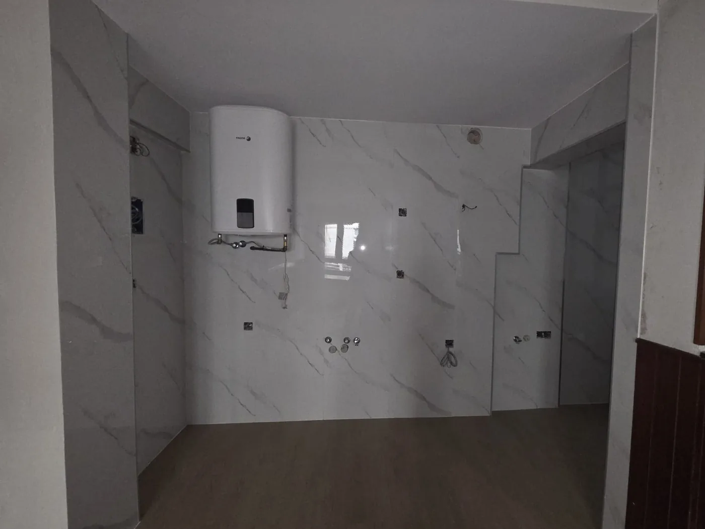 Cocina reformada con alicatado tipo mármol y suelo de madera