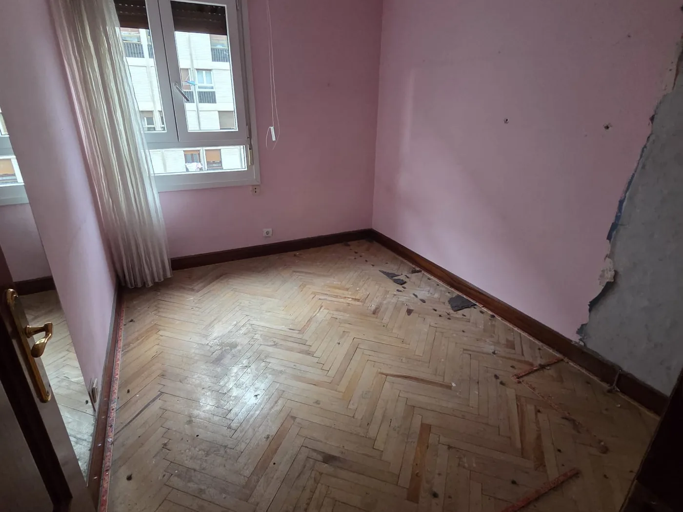 Dormitorio antes de la reforma, con parquet de espiga dañado